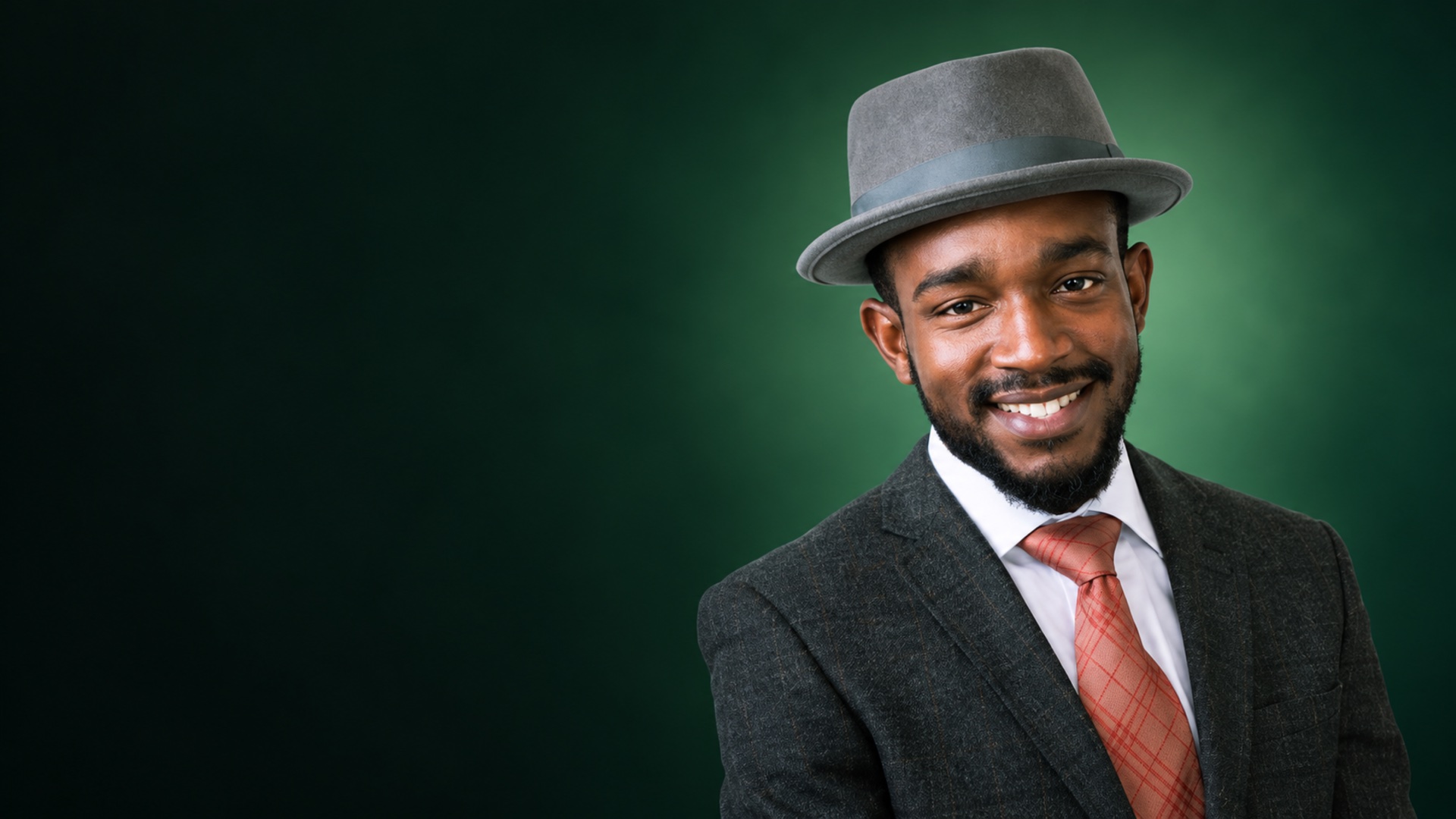 Lewie Allen smiling in a grey fedora and suit against an emerald gradient